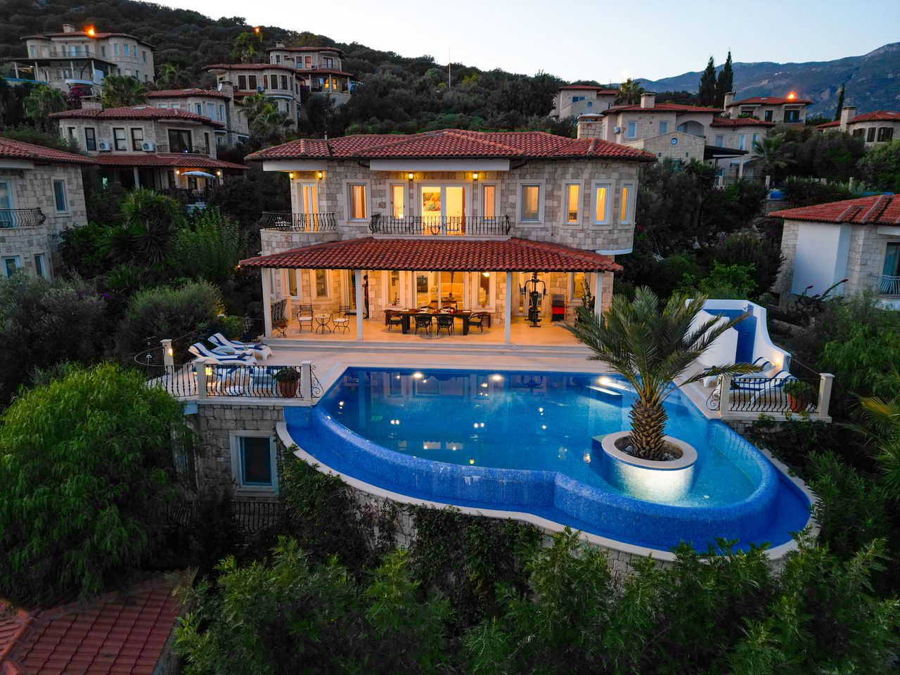 A luxury villa with a pool glowing at dusk